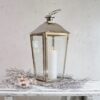 Large silver candle lantern on white bench with tealights
