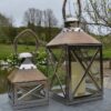 Set of 2 mango wood and silver lanterns outside by pond