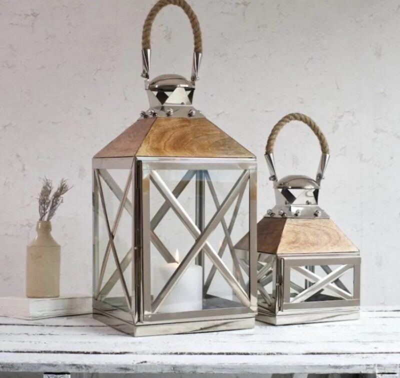 large silver candle lanterns on white wooden shelf