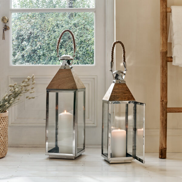 Mango wood and metal candle lanterns on white floor in front of window