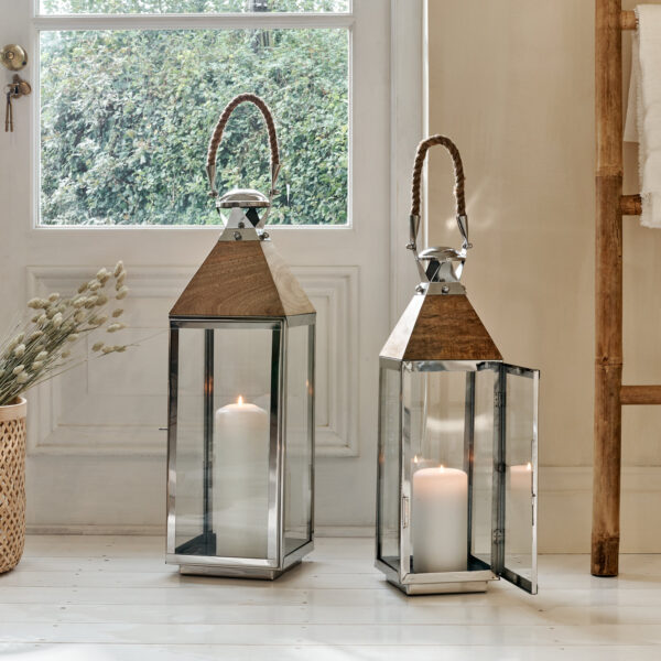 Tall silver floor lanterns on white floor in front of window