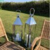 Large outdoor stainless steel candle lanterns by rattan chairs