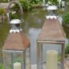 Stainless steel and wood candle lanterns outside by pond