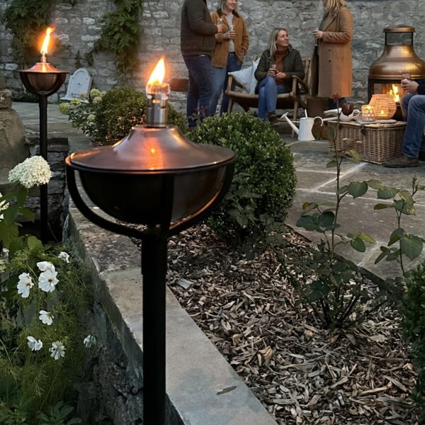 garden oil lamp with people socialising In the background