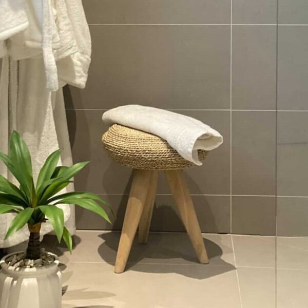 small wicker stool in bathroom with plant and towel