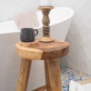 Rustic wooden stool close up with wood coaster and coffee cup with wooden candlestick, in bathroom