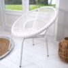 Wicker white tub chair on white wooden floor with rug and bamboo lantern