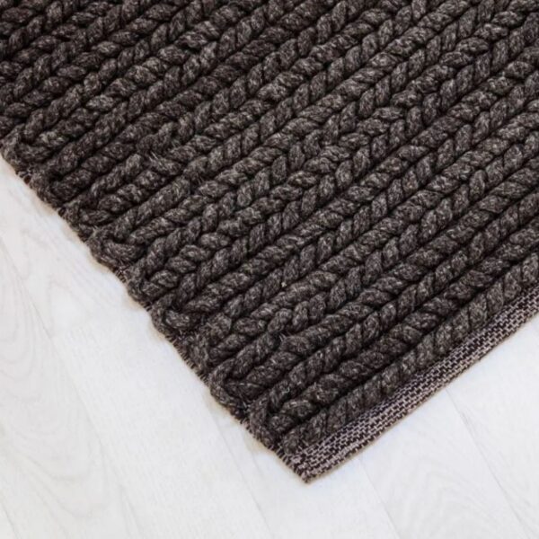 Close up of dark grey handmade woven rug Sofia on white floor