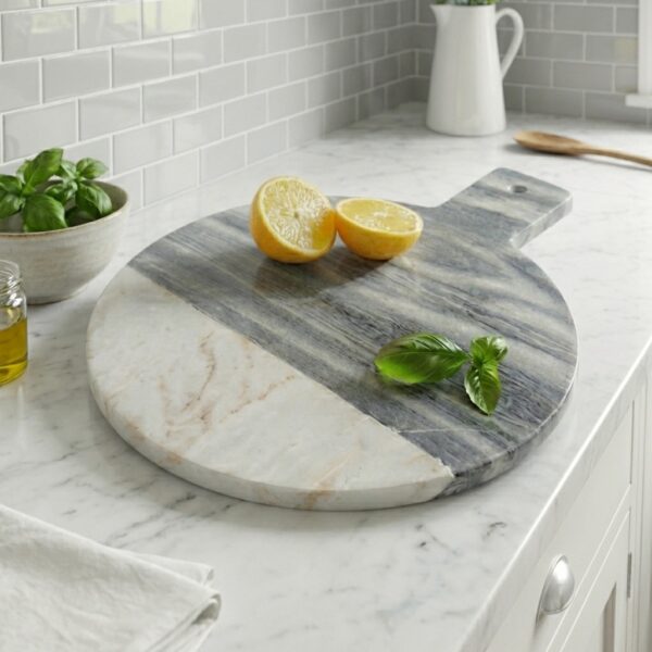 Marble round chopping board, on kitchen worktop with lemons and herbs