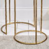 Close up of brass and glass nest of tables on rug and wooden floor.