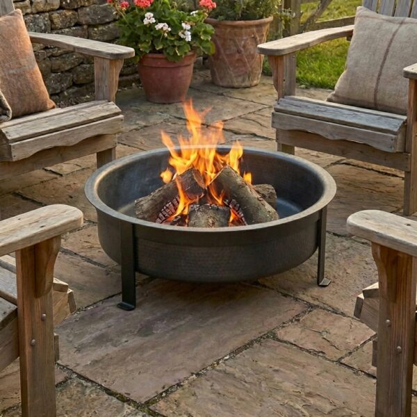 Black metal fire pit on patio with wooden chairs around it