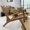 Teak rattan armchair in living room with rug and cushions.