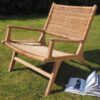Wicker garden armchair outside on grass with book