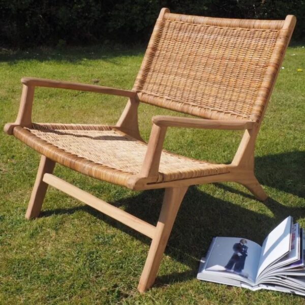 Wicker garden armchair outside on grass with book
