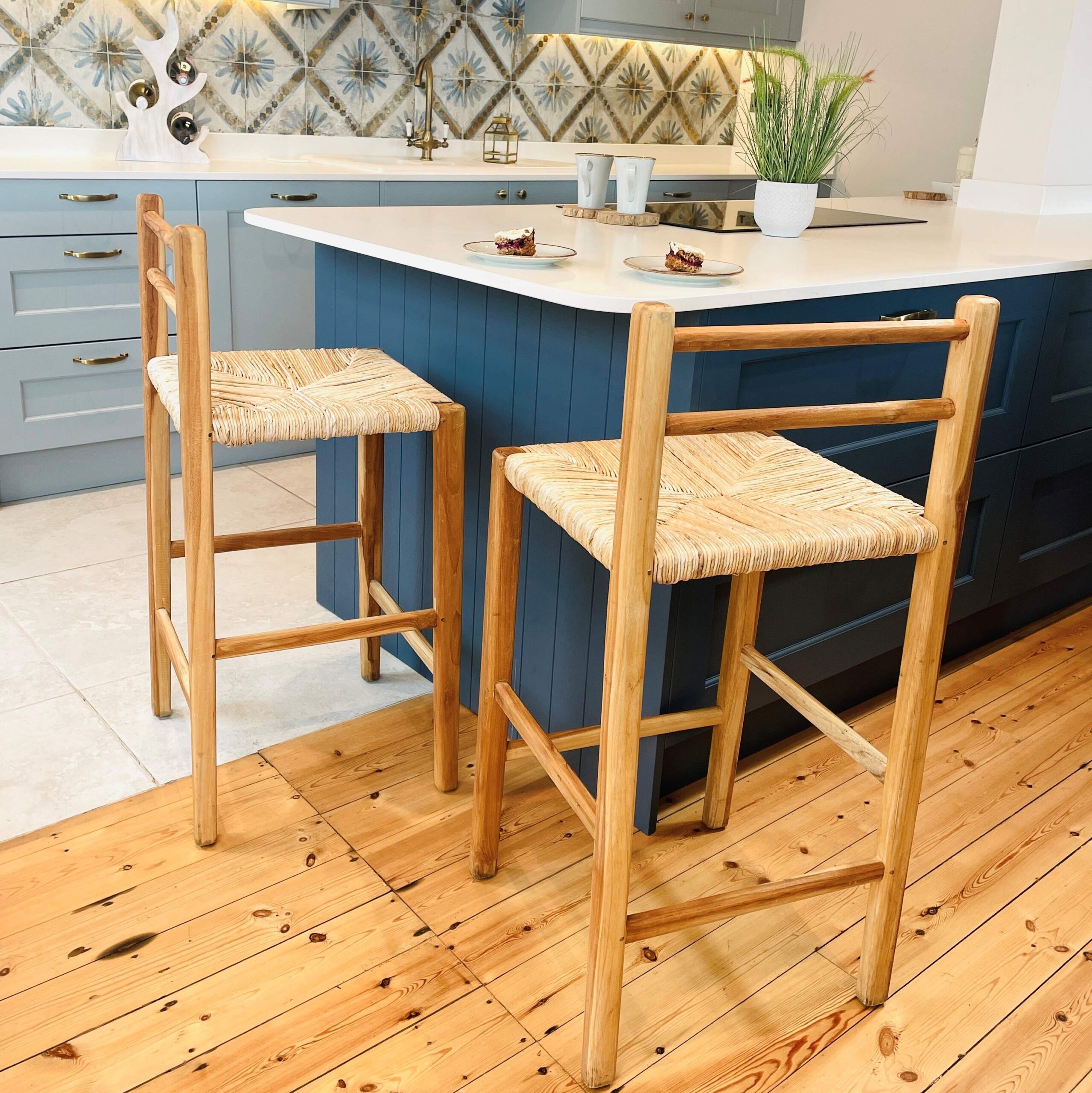 Two wicker kitchen stools in front of blue kitchen island