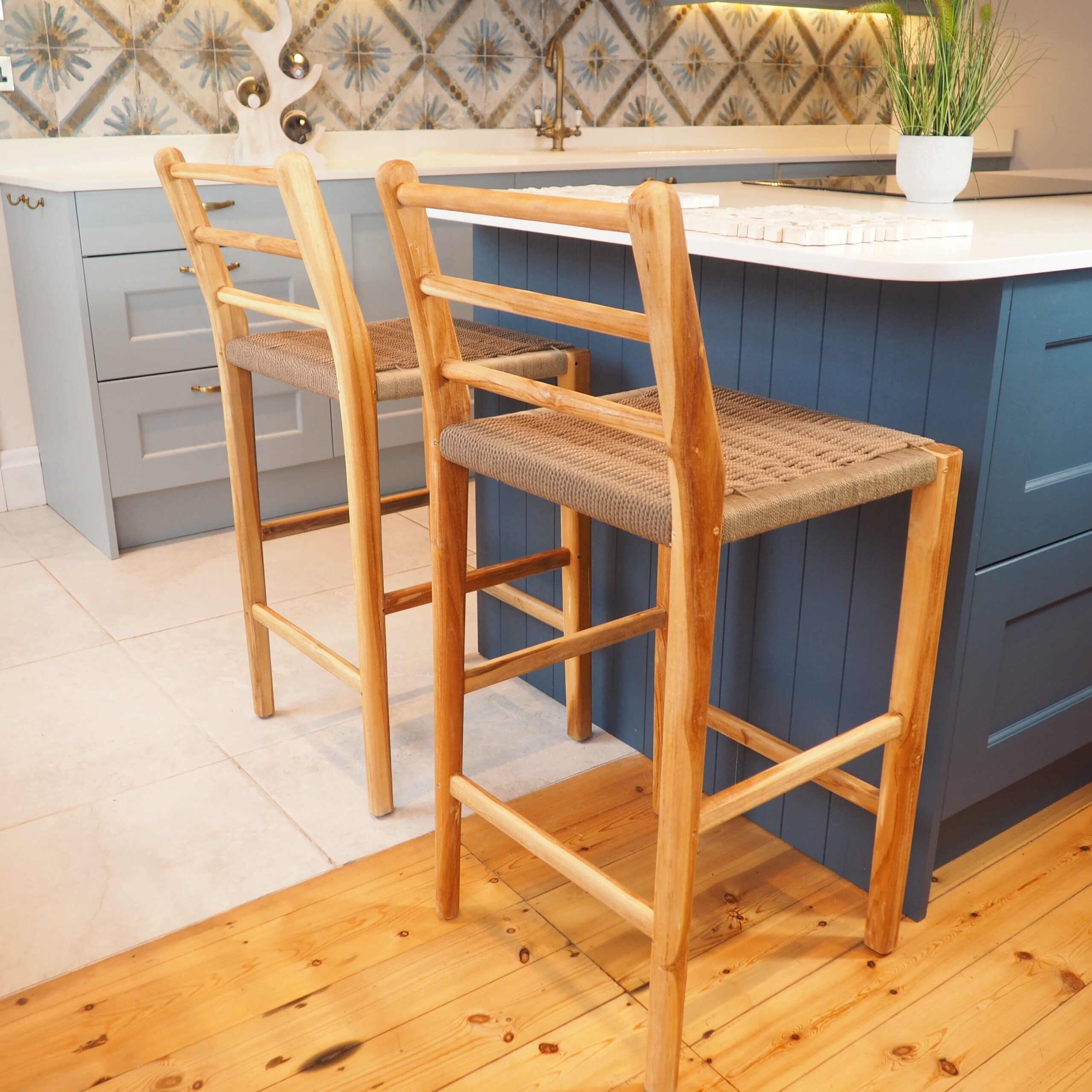 Natural wicker kitchen stools in kitchen setting in front of blue island