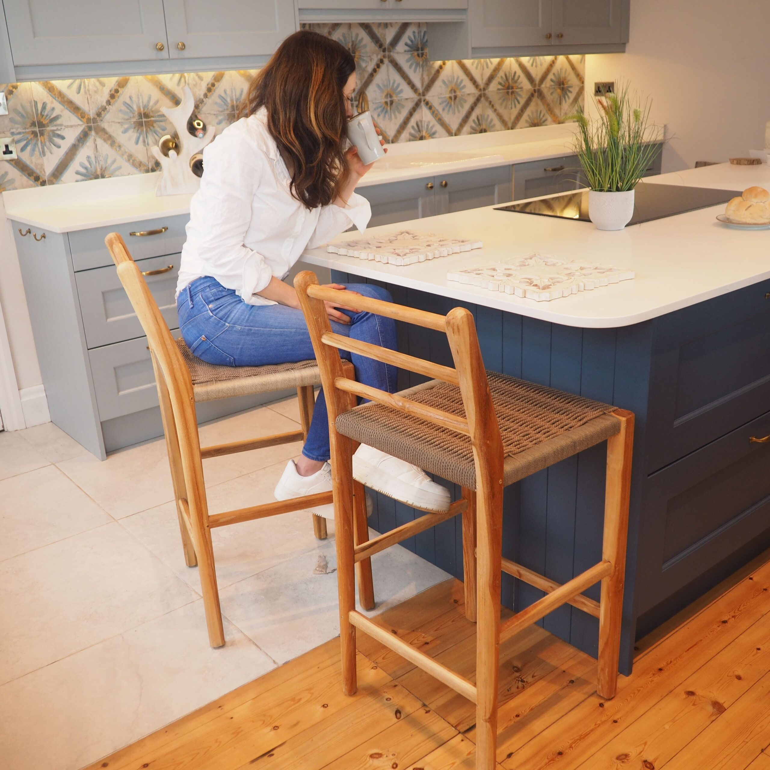 Woman sat on natural kitchen stool in blue kitchen space