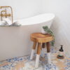 small wooden rustic stool in bathroom setting with plant