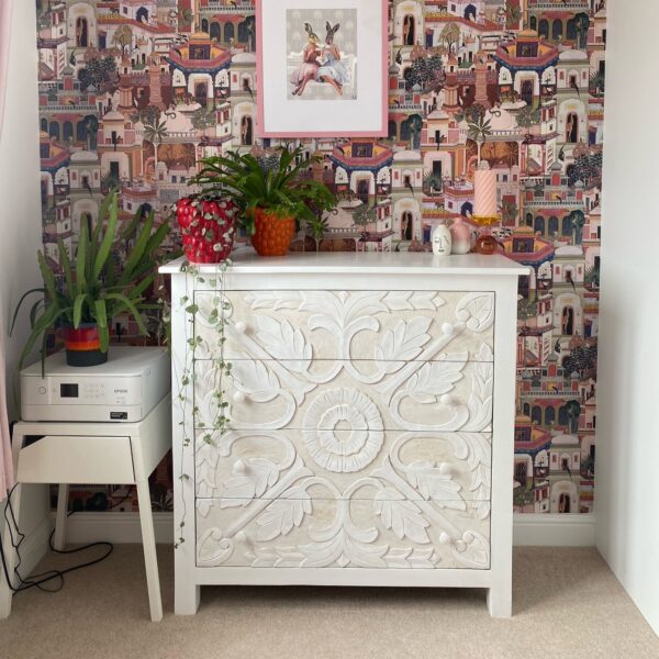 White chest of draws on carpet in room next to bedside table and plants