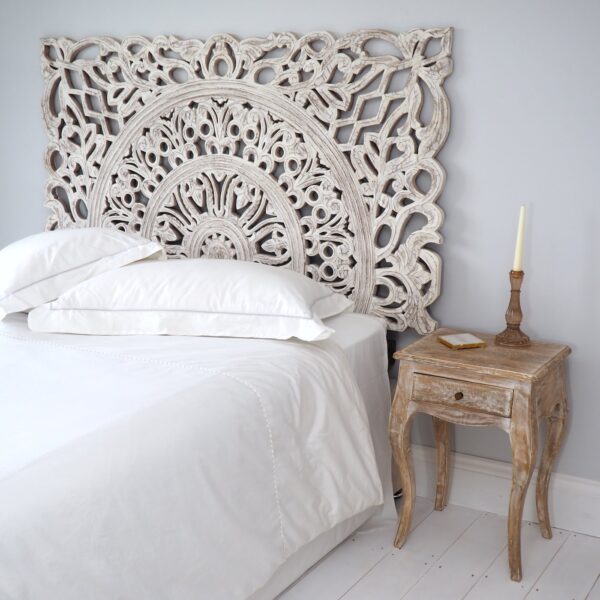 White Carved Wooden Headboard on wooden floor next to wooden bedside table