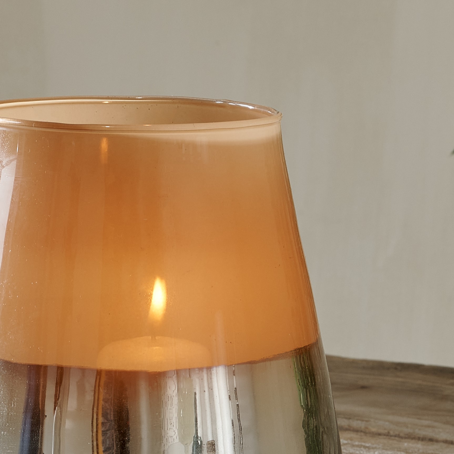 Top of metallic hurricane lantern on wooden table with candle