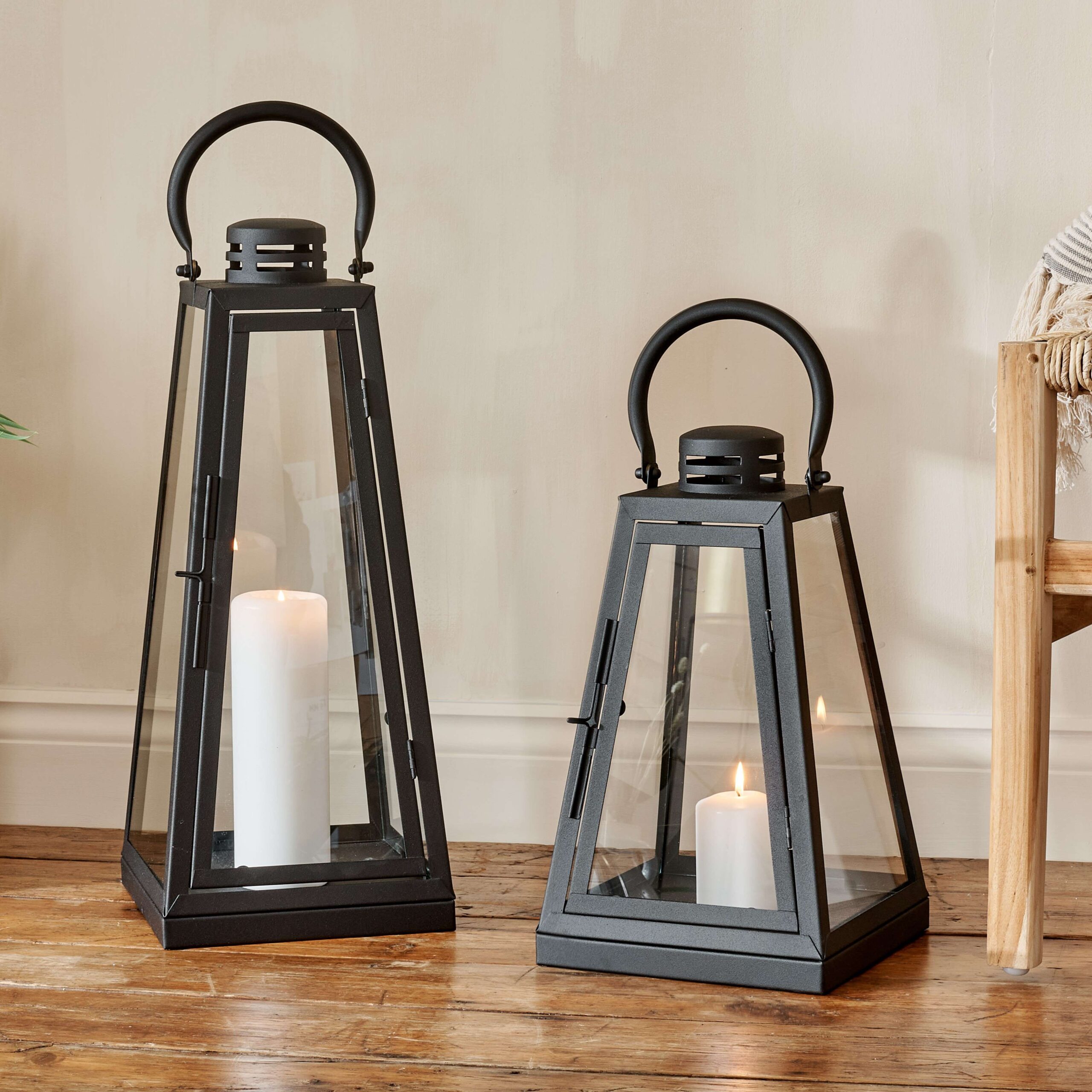 black candle lanterns on wooden floor with chair leg