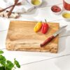 Rustic wood chopping board on white wooden table, with peppers and knife