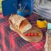 Wooden platter board in camping setting with food and cups