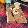 Wooden chopping board with scones, jam and cream on table cloth