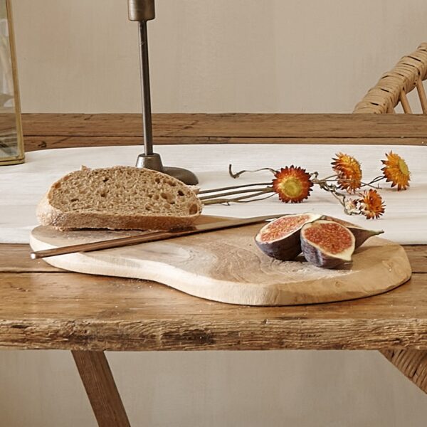 Rustic wood serving board on wooden table with figs and flowers