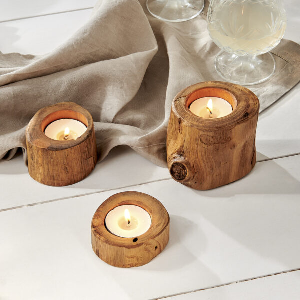 Wooden tealight holders on white wooden floor, with glass and material