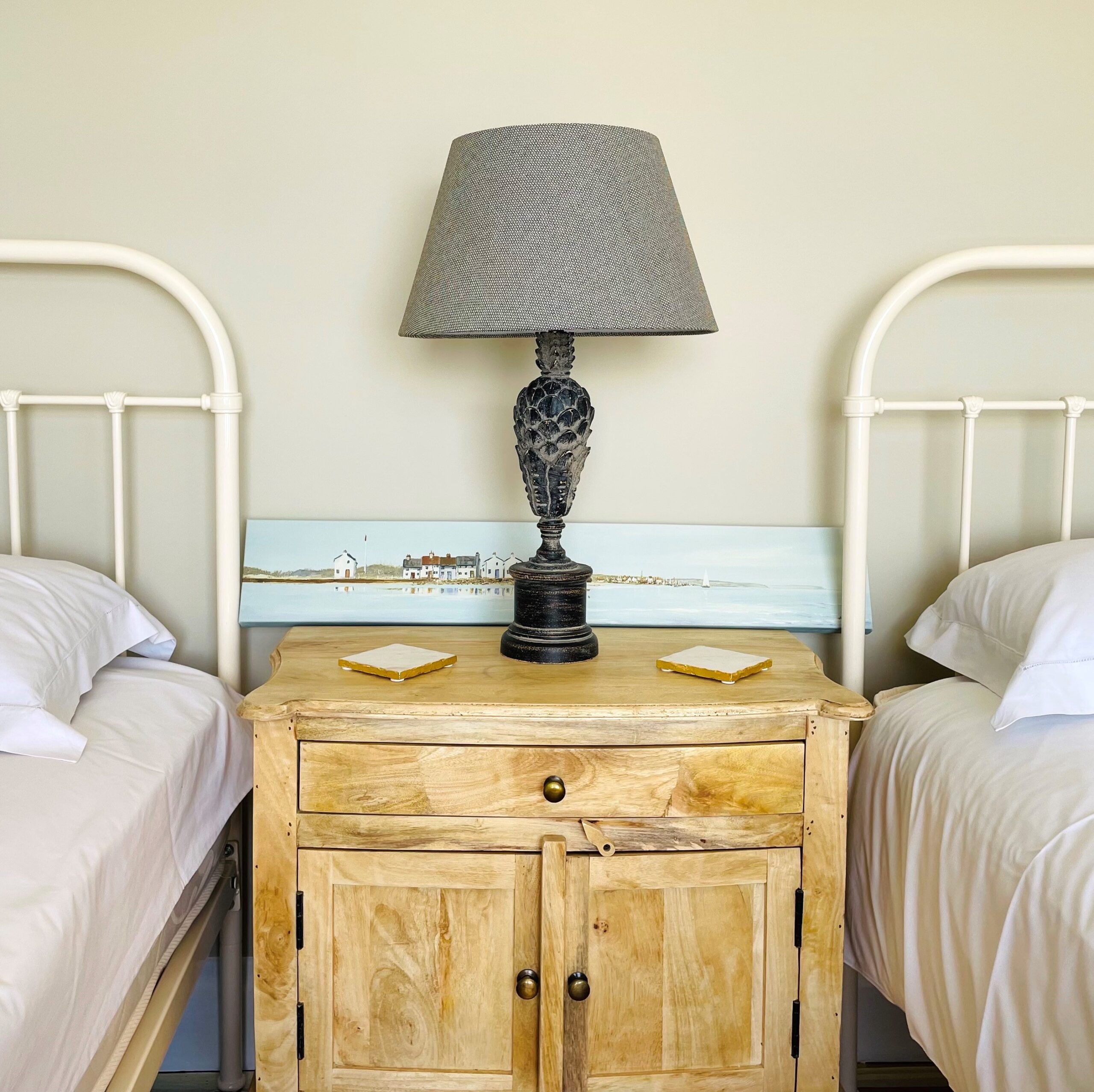 Large wooden Eden bedside table between beds with lamp