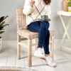 Woman sat on rattan dining chair on white floor with table