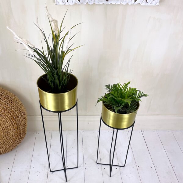 brass plant stands with green plants and wicker pouffe