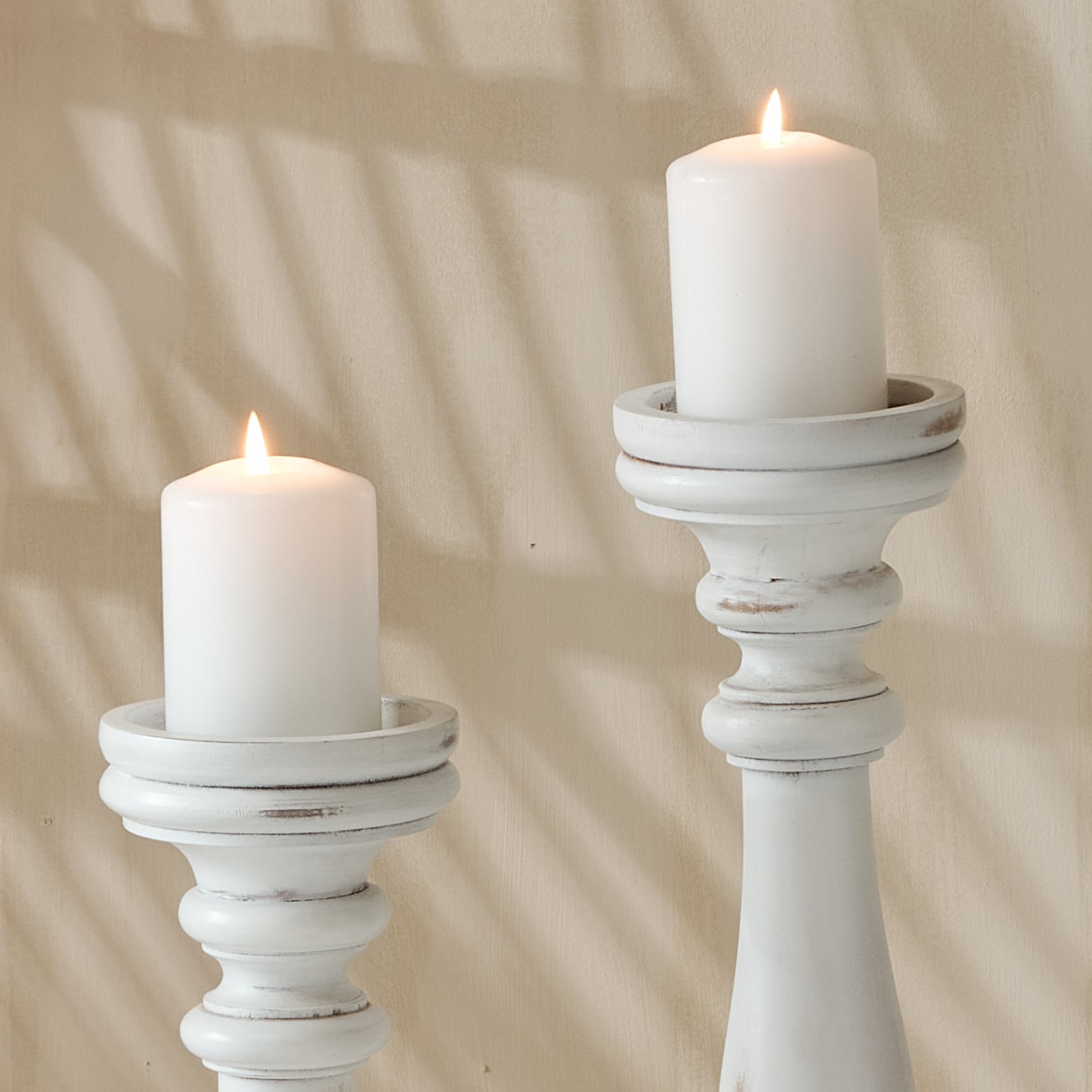 2 tall white wooden candlesticks with white pillar candles