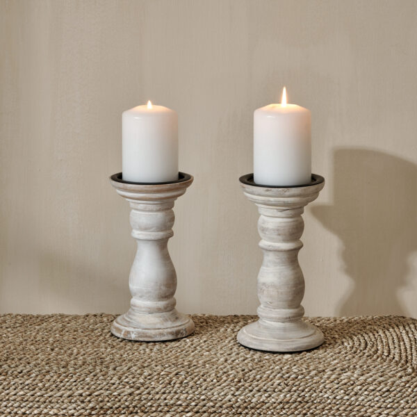 White wooden candlesticks on wicker bench