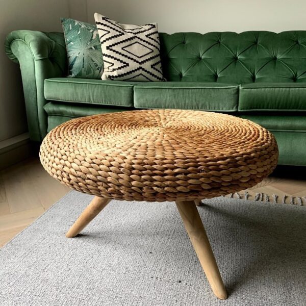 Wicker coffee table in living room with velvet green sofa