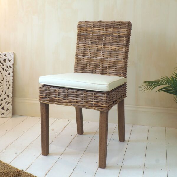 Natural wicker dining chair with cushion on white wooden floor