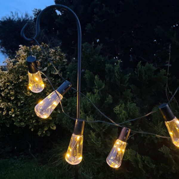 Solar powered outdoor string lights on shepherds hook at night