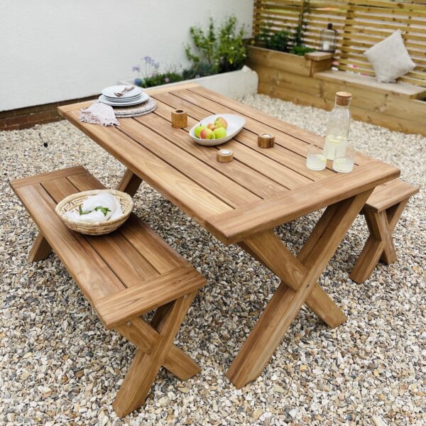 Garden Table and bench outdoors with plants, tableware, drinks and food.