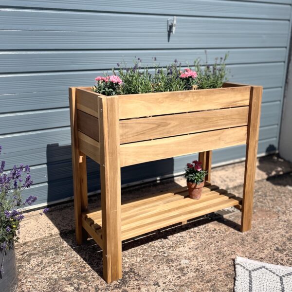 Wooden plant stand in garden with flowering plants