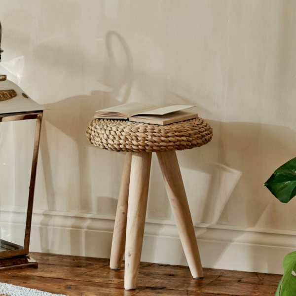 small wicker stool on wooden floor with book and plant