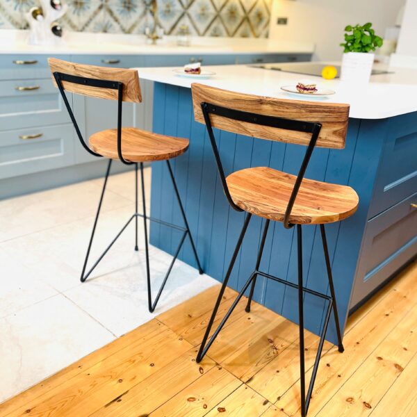 Two industrial bar stools in front of blue kitchen island on wooden floor