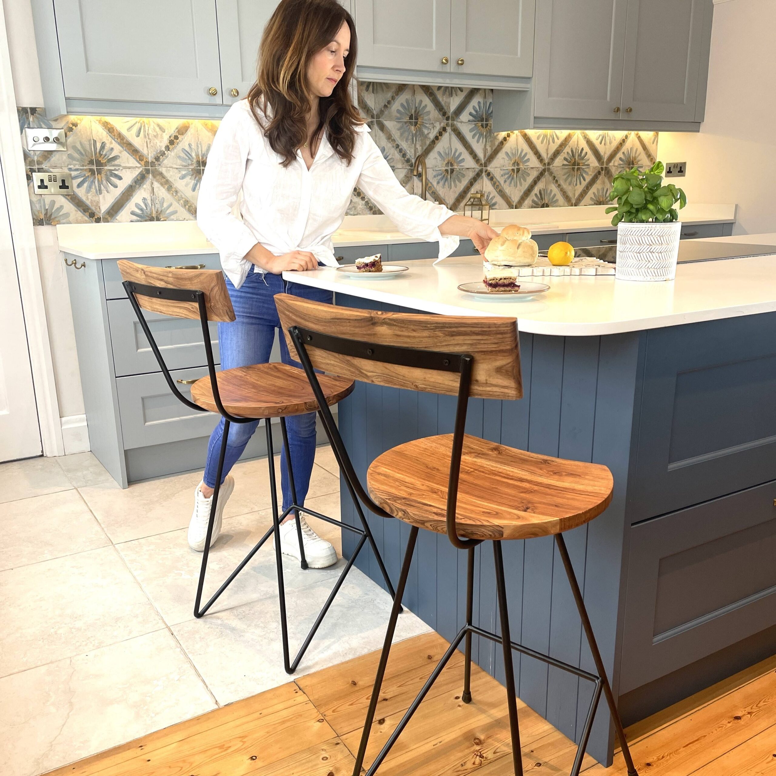Industrial bar stools with wood in kitchen setting with woman by blue kitchen island