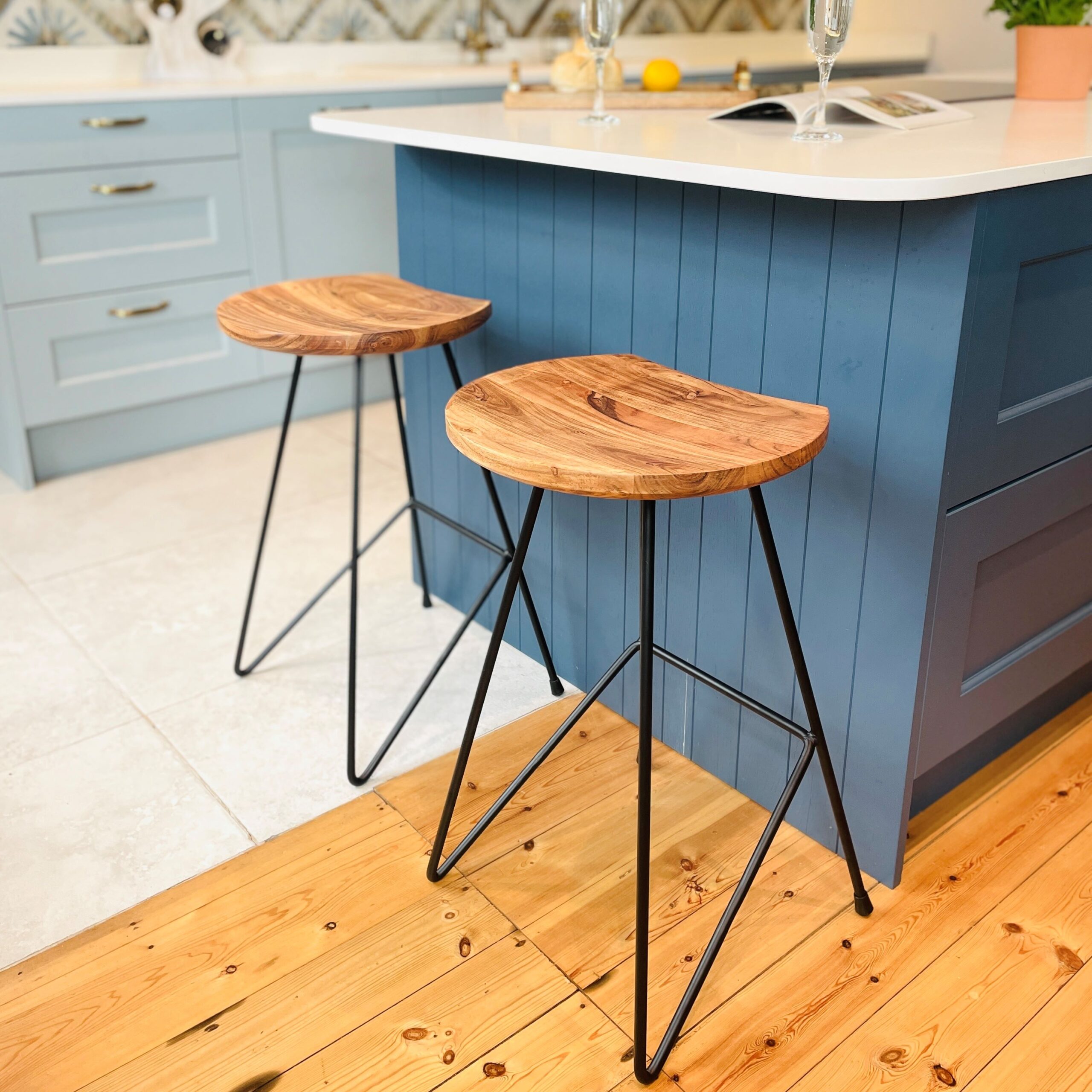 Two industrial bar stools on wooden floor in front of blue kitchen island