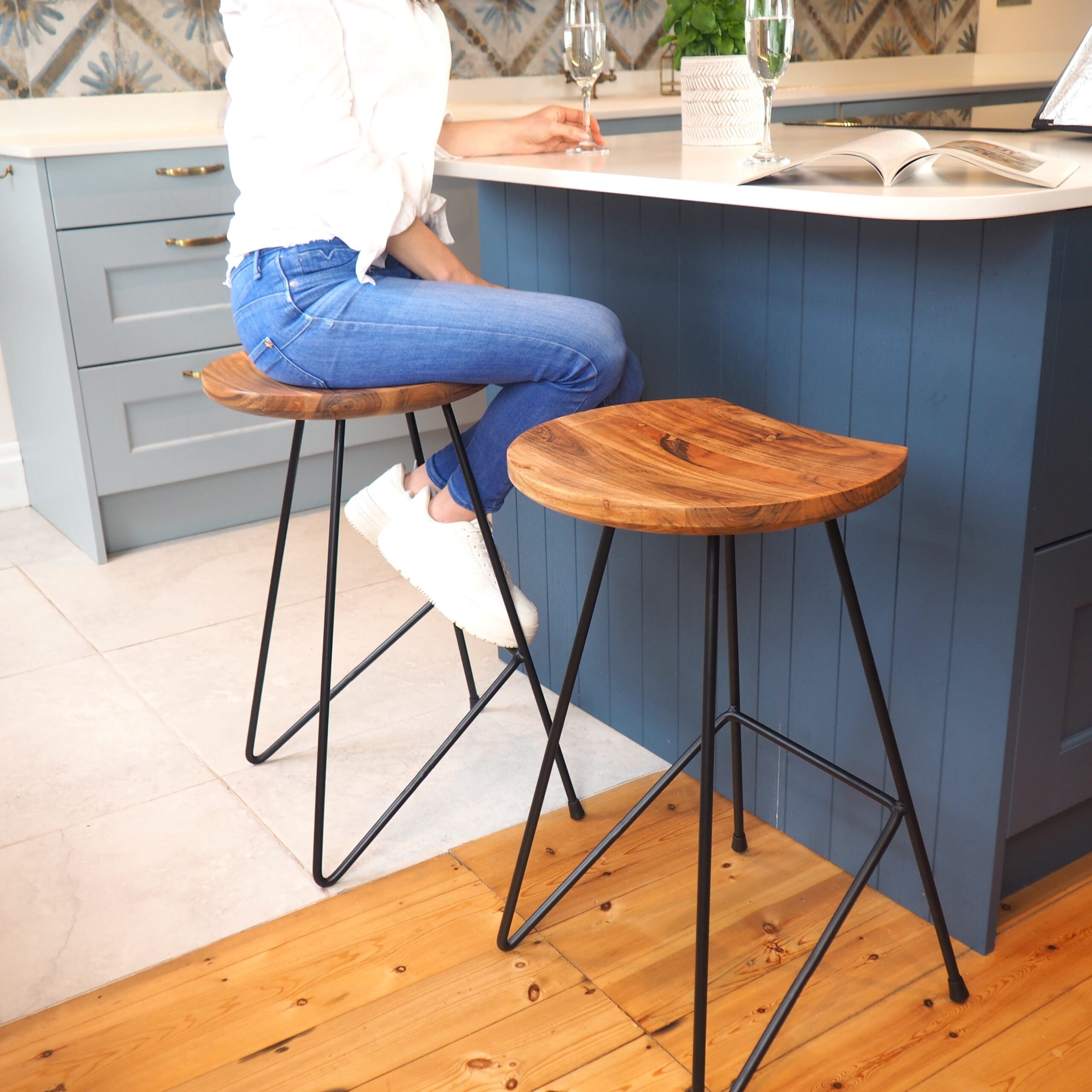 Woman sitting on industrial bar stool in front of blue kitchen island