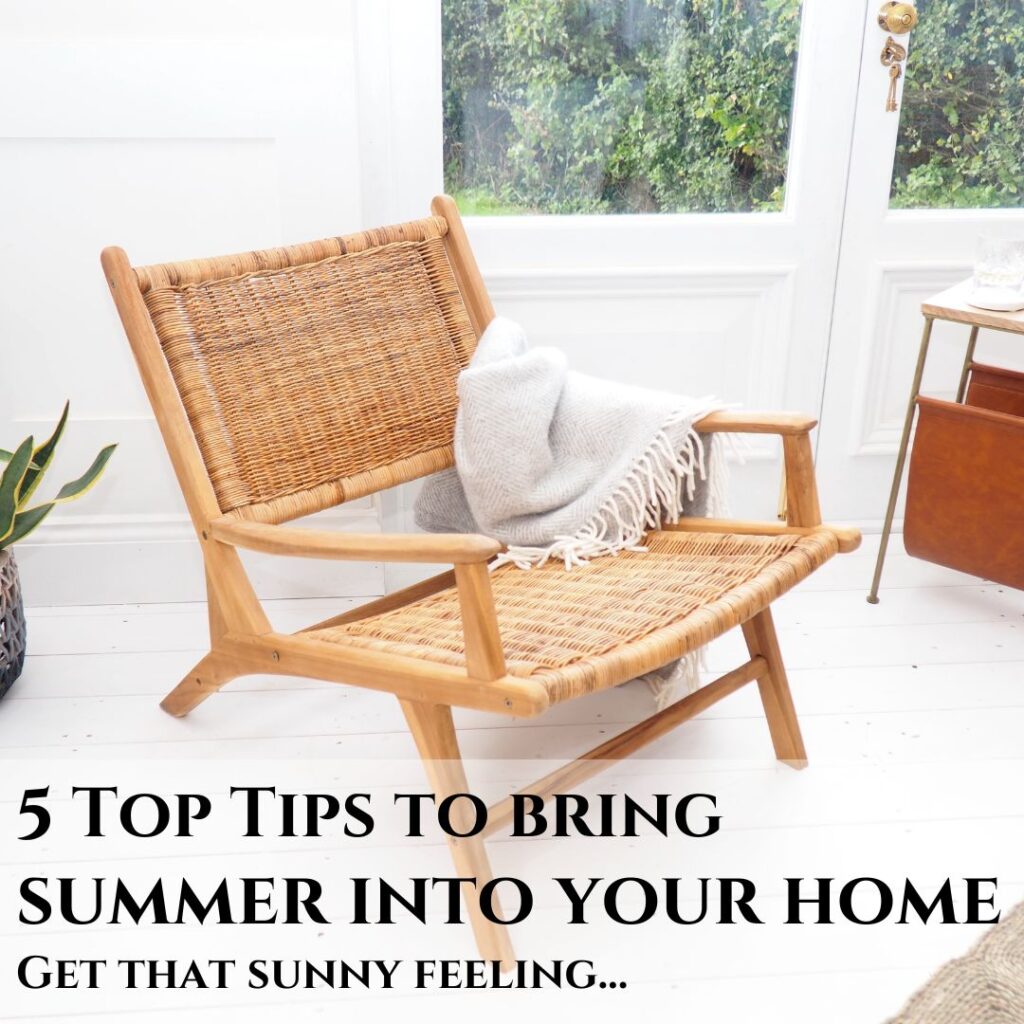 Teak and rattan chair inside on white wooden floor, with blanket on arm, in front of window. Summer into your home