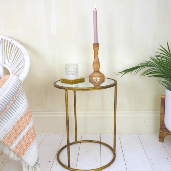 Small brass round table, candle on mirrored top with white planter and white wicker chair